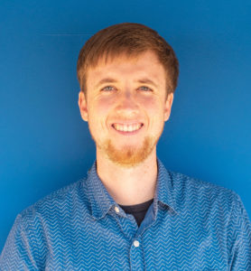 Samuel Dahlin smiles at the camera in front of a blue background