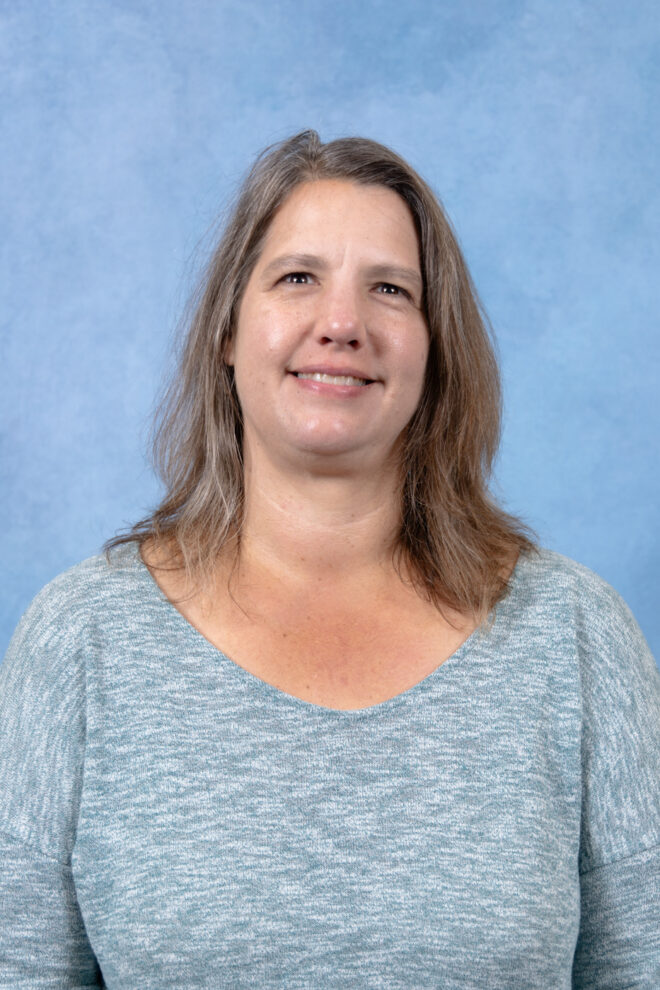 Amy Barrett smiles at the camera in front of a blue background