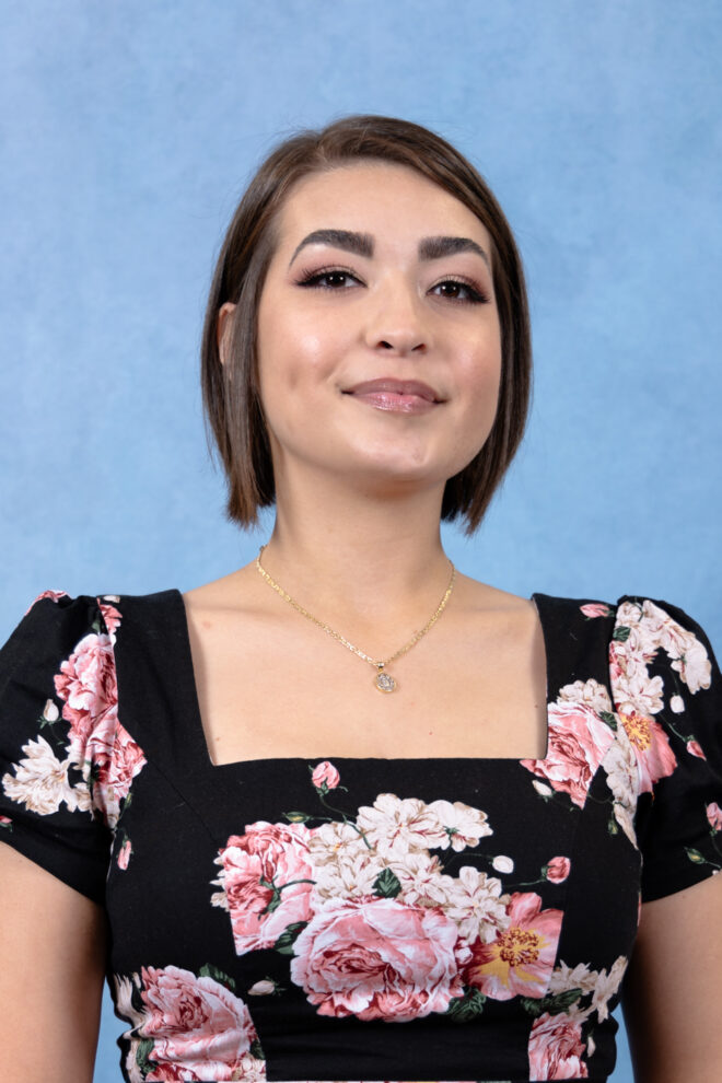 Ciara Ontiveros smiles at the camera in front of a blue background