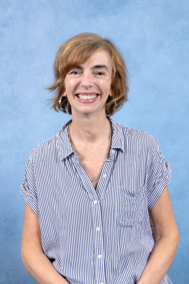 Laura Lundy smiles at the camera in front of a blue background